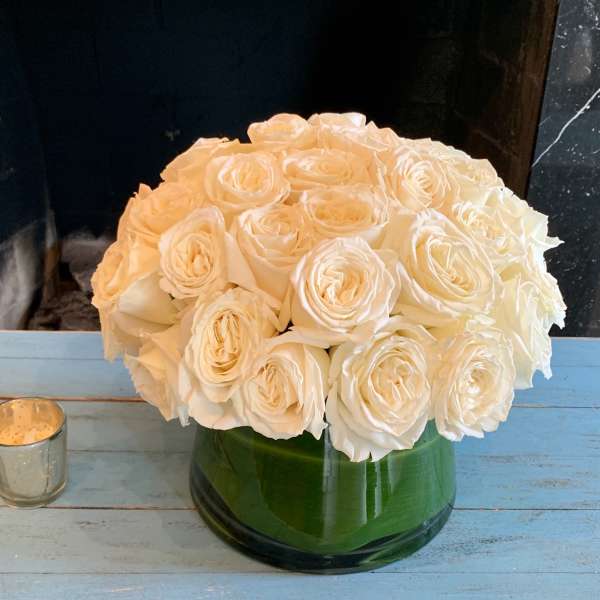 Round bouquet of white roses in a green glass vase