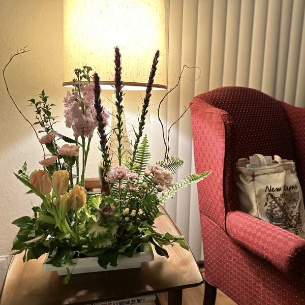 Mixed floral arrangement in a white rectangular container on a table