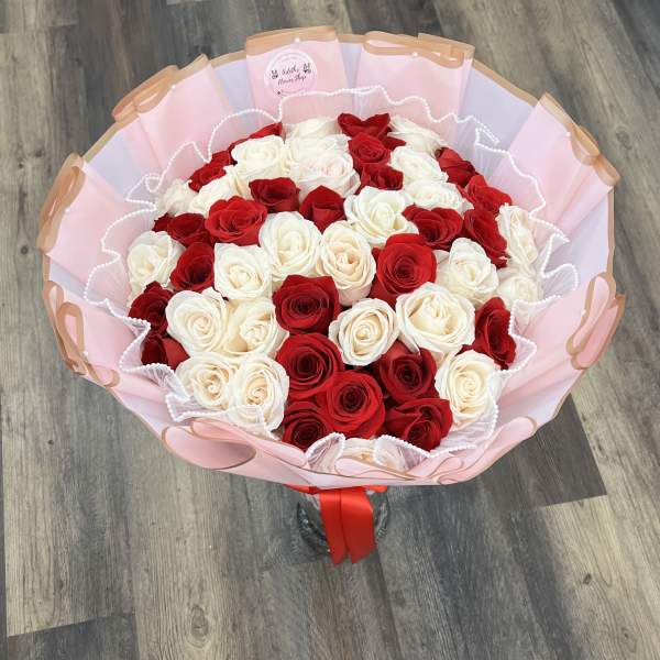 Bouquet of red and white roses wrapped in pink paper with a red ribbon