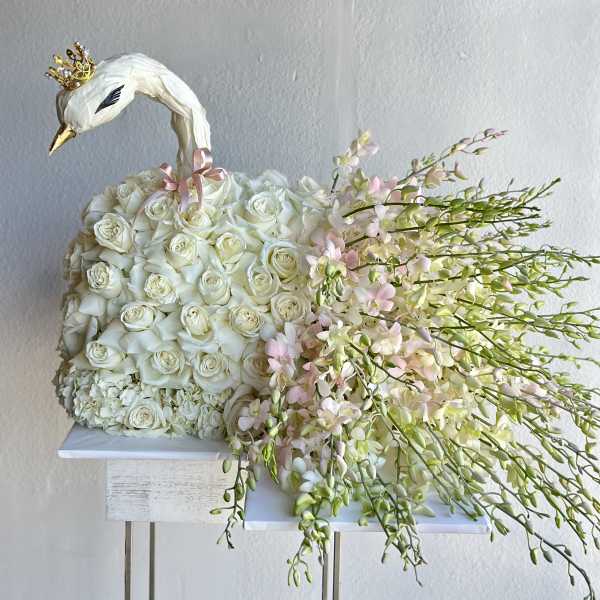 White rose arrangement shaped like a swan with pink orchid sprays