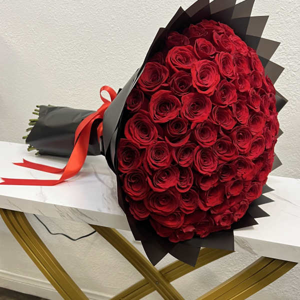 Large bouquet of red roses wrapped in black paper with a red ribbon
