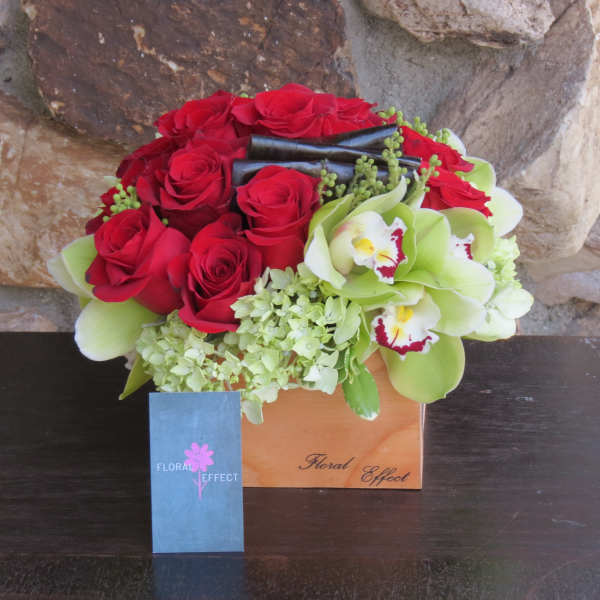 Red roses and green orchids in a wooden box