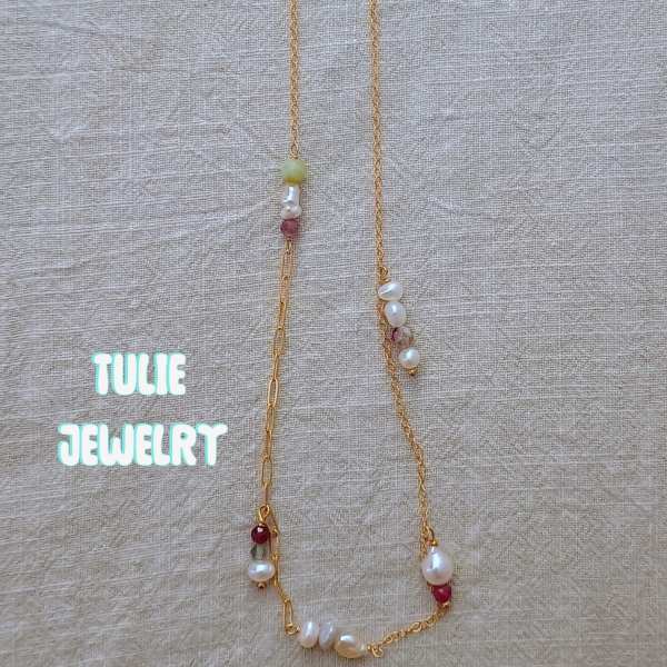 Gold necklace with pearl and bead accents on beige fabric