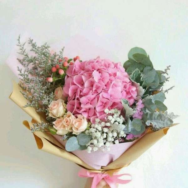 Bouquet of pink hydrangea and peach roses wrapped in paper