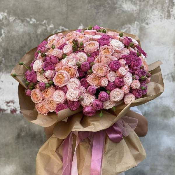Large bouquet of pink and peach roses wrapped in brown paper with pink ribbons