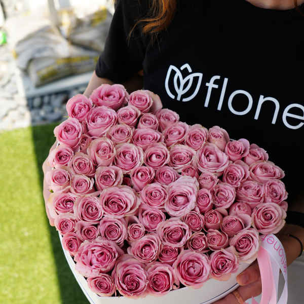Heart-shaped box filled with pink roses and a pink ribbon