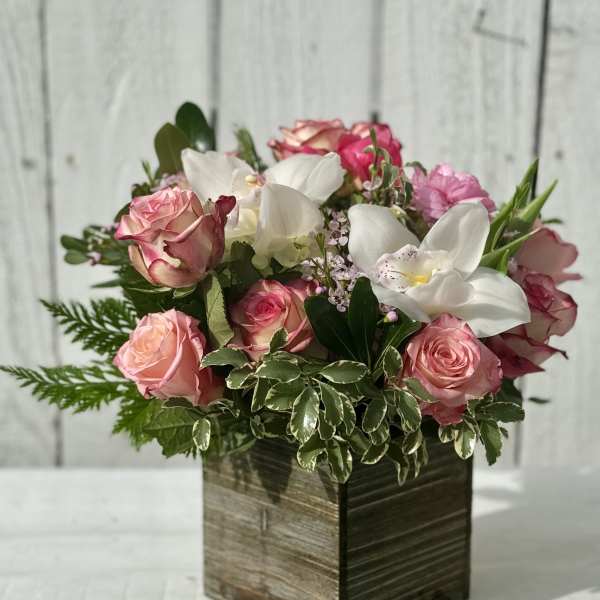 Pink roses and white orchids arranged in a square wooden box
