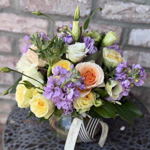 Bouquet of peach, white, and yellow roses with purple flowers