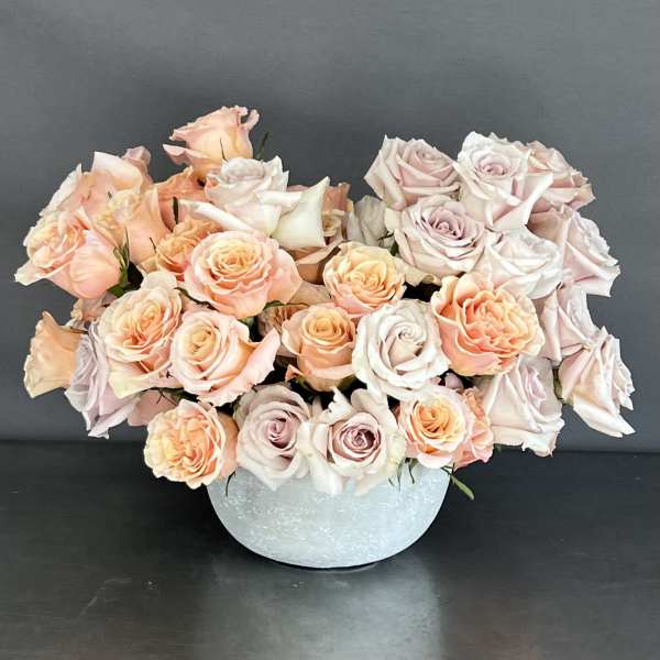 Arrangement of pale pink and peach roses in a light blue vase