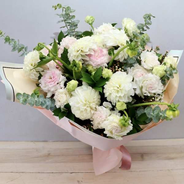 Bouquet of white and pale pink flowers wrapped in pink paper