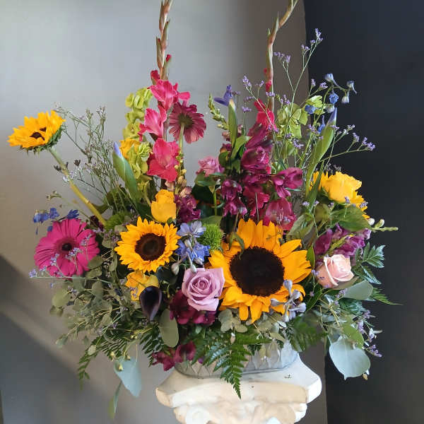 Colorful mixed flower arrangement with sunflowers, roses, and tall stems in a vase