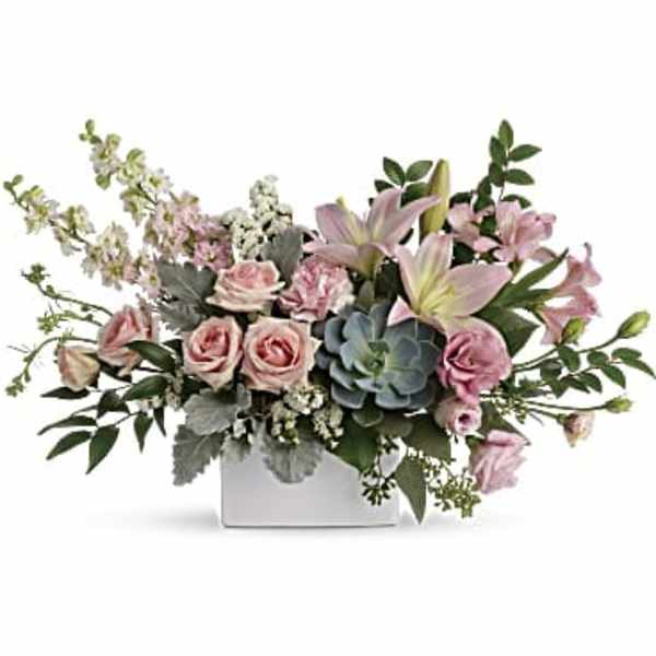 Low arrangement of pink roses, lilies, and a central succulent in a white rectangular vase
