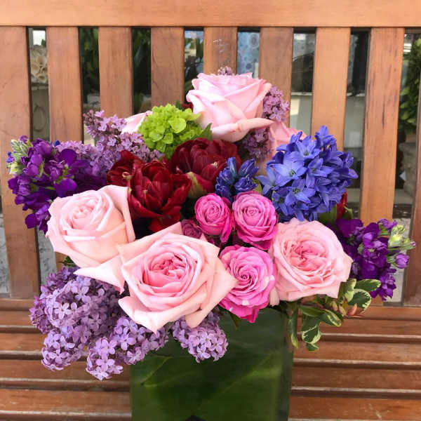 Mixed bouquet of pink, purple, and red flowers in a green vase