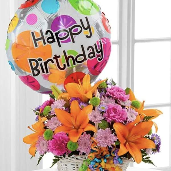 Birthday balloon above a colorful flower basket in a white basket