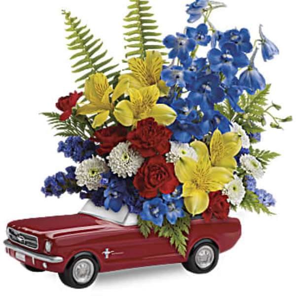 Bright mixed flower arrangement in a red ceramic car-shaped container