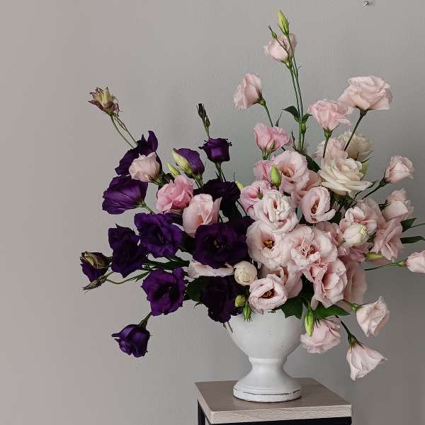 Pink and purple flowers arranged in a white vase