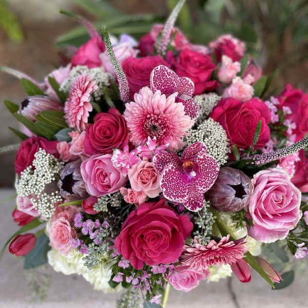 Pink and magenta bouquet with roses, orchids, and daisies