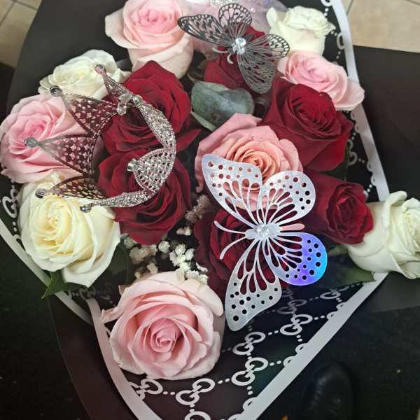 Bouquet of pink, red, and white roses with a plush cat topper