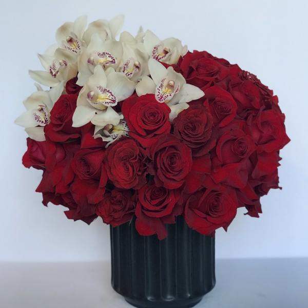 Red roses and white orchids arranged in a black vase