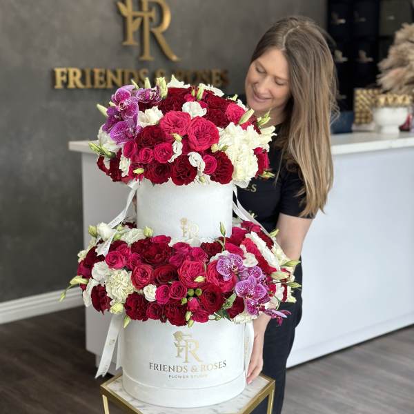 Two-tier hatbox arrangement of red, pink, white, and purple flowers