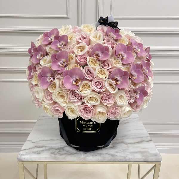 Large bouquet of pink and white roses with purple orchids in a black hat box
