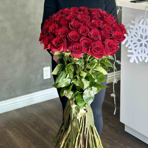 Large bouquet of red roses with long stems and ribbon ties