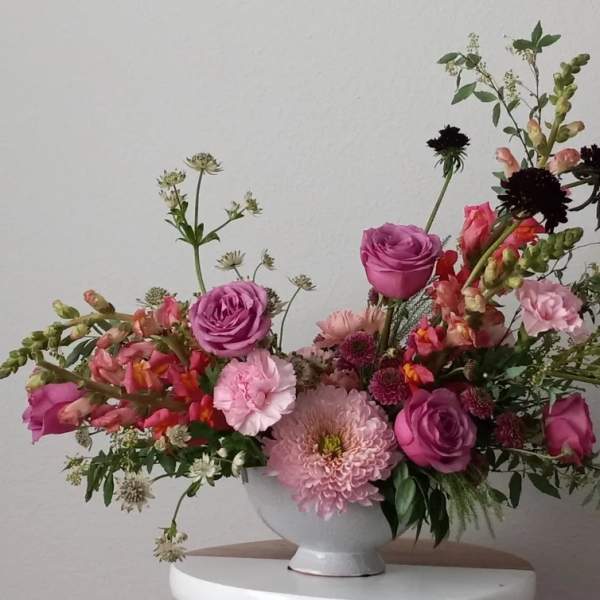 Pink and purple mixed flower arrangement in a white vase
