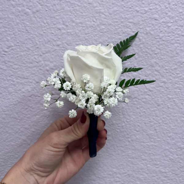 White rose boutonniere with baby's breath and fern leaves