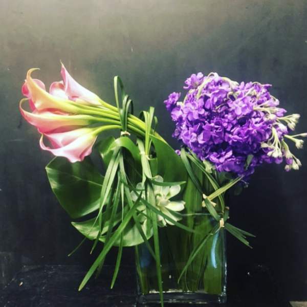 Bouquet of pink calla lilies and purple flowers in a glass vase