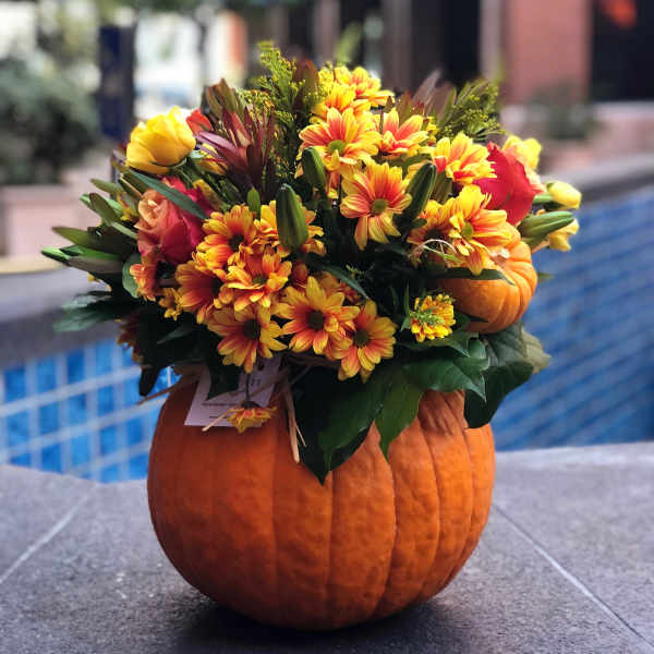 Fall bouquet of yellow and orange flowers arranged in a pumpkin