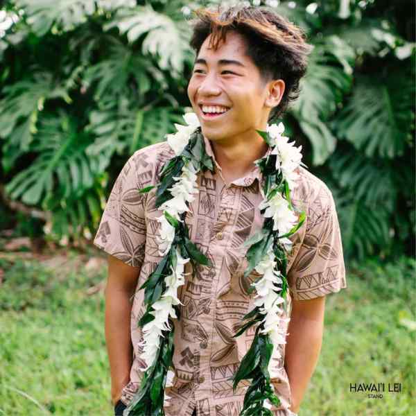 Person wearing a white flower lei over a patterned shirt