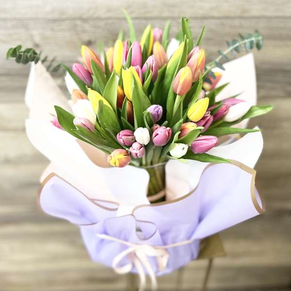 Bouquet of multicolored tulips wrapped in lavender paper