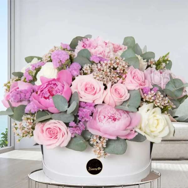 Pink and white roses and peonies arranged in a white hat box