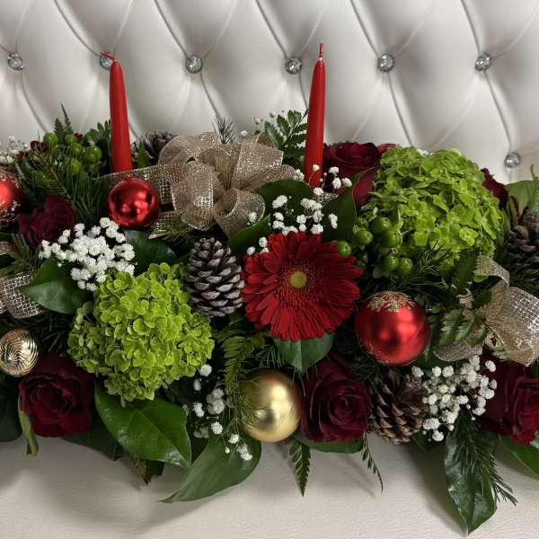Holiday centerpiece with red roses, green hydrangeas, candles, and ornaments