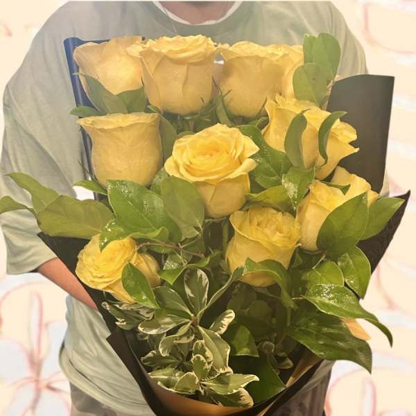 Bouquet of yellow roses wrapped in black paper with a yellow ribbon