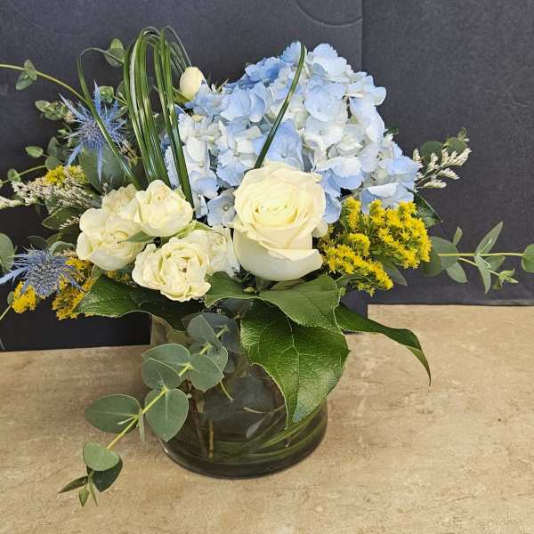 Blue hydrangeas and cream roses in a glass vase