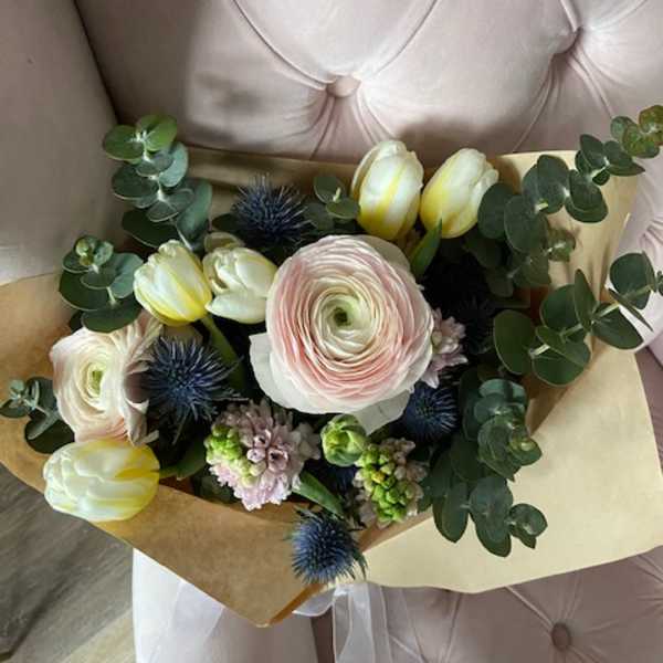 Bouquet of pale tulips and ranunculus with eucalyptus and blue thistle