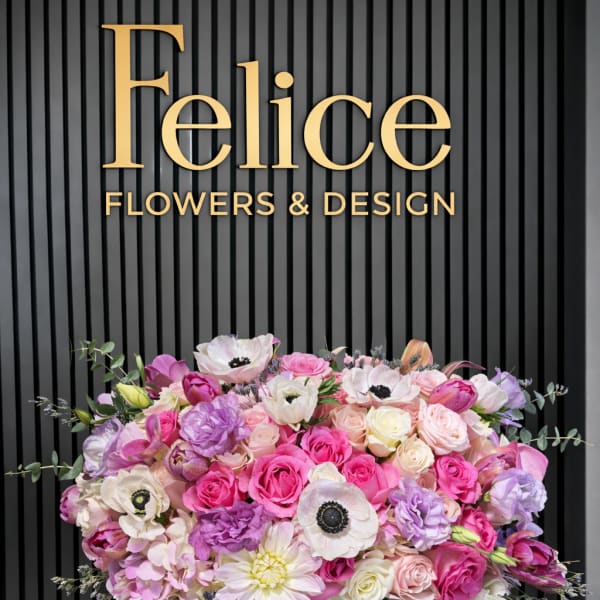 Large pink and lavender flower arrangement in a white pedestal vase