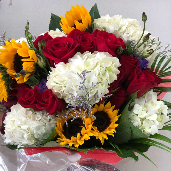 Bouquet of red roses, white hydrangeas, and sunflowers wrapped in clear plastic