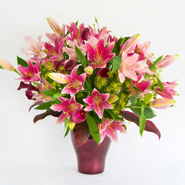 Pink lilies arranged in a burgundy vase