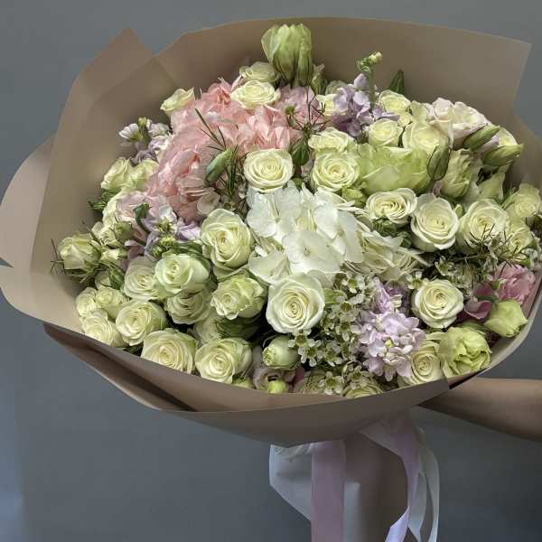 Bouquet of pale roses and pink flowers wrapped in tan paper