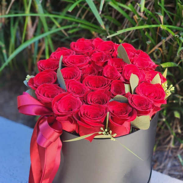 Red rose bouquet in a black hat box with a pink ribbon