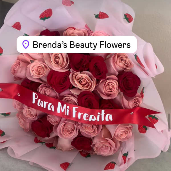 Bouquet of pink and red roses wrapped in strawberry-patterned paper