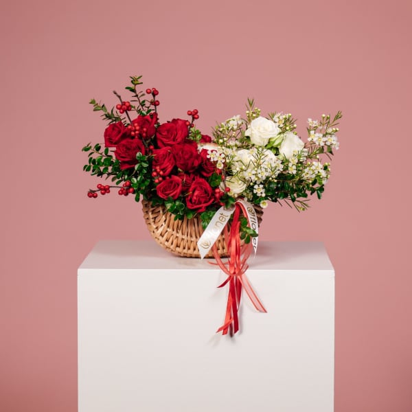 Basket arrangement of red and white roses with berries on a pedestal