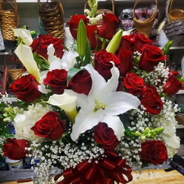 Large bouquet of red roses and white lilies in a glass vase with a red ribbon