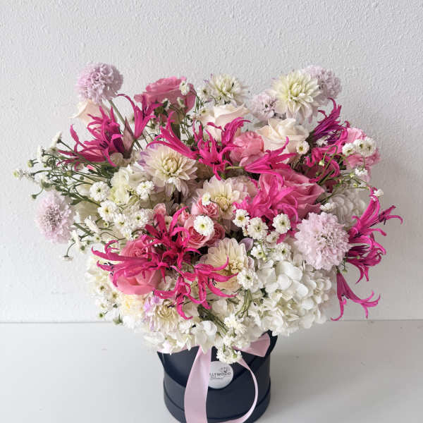 Pink and white mixed flower arrangement in a black hat box with a ribbon