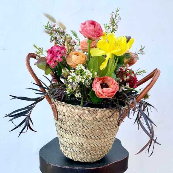 Colorful mixed flower arrangement in a woven basket