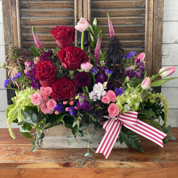 Mixed bouquet of red and pink roses with purple accents and a striped ribbon
