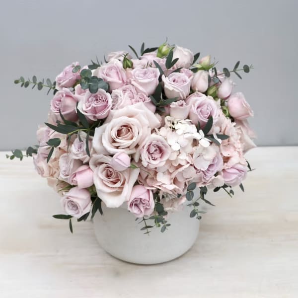 Pink roses and hydrangeas arranged in a white vase