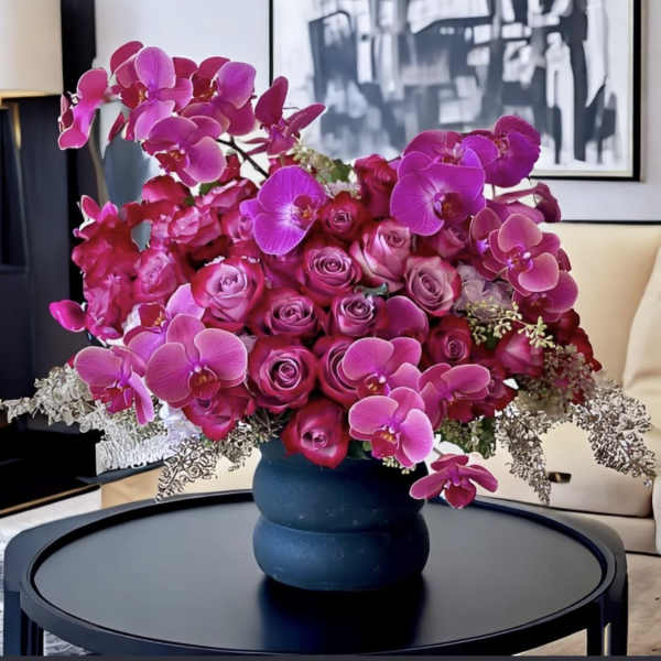 Pink orchids and roses arranged in a dark vase on a table